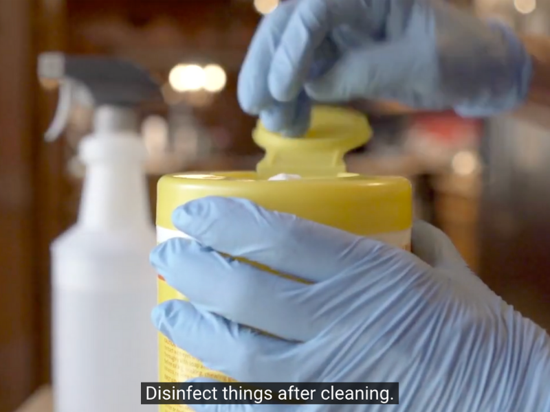 an image of someone wearing gloves and using disinfectant wipes.