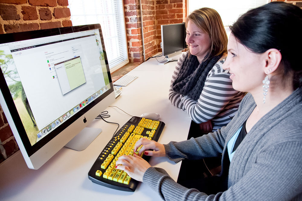 Two women using an assistive technology keyboard.