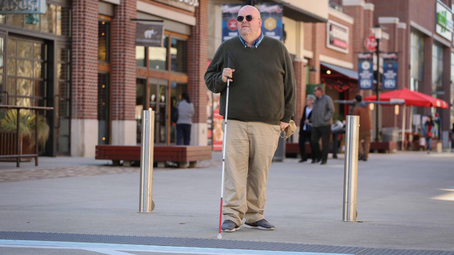 A blind man using a cane to navigate independently.