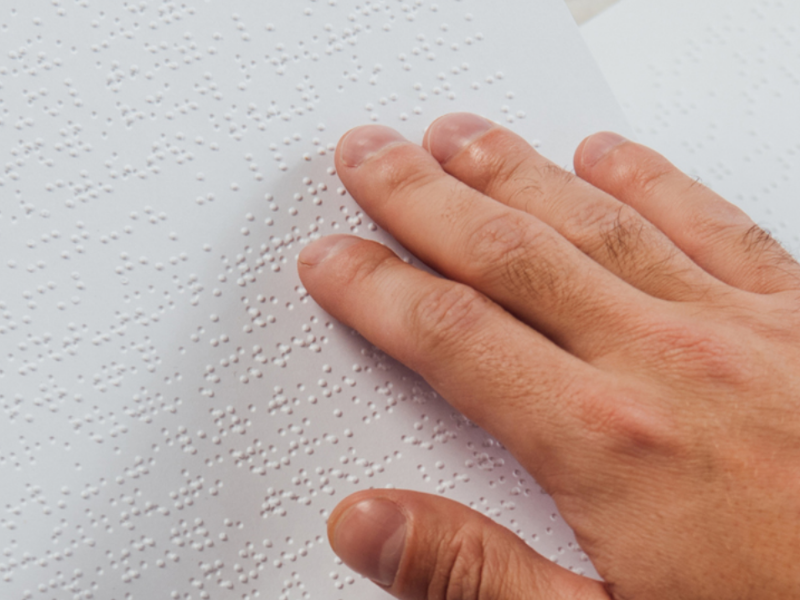 a man's hand reading braille.