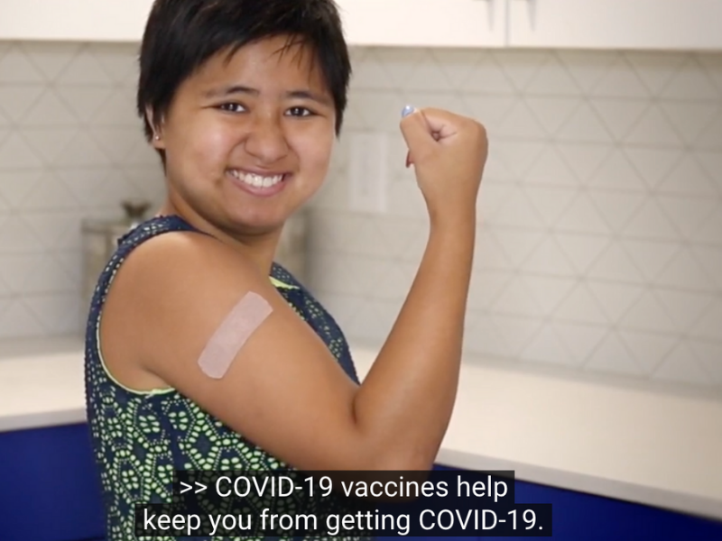 a young woman proudly showing a bandaid you receive after getting the vaccine.