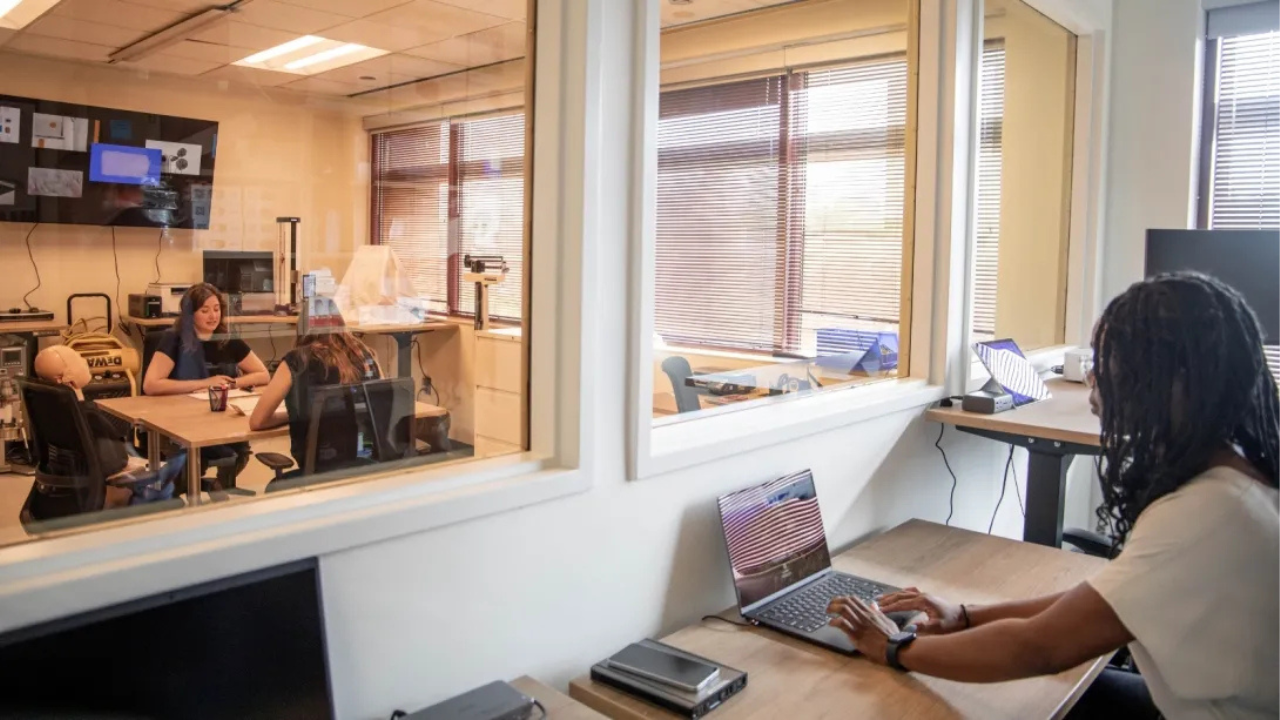 People doing research with a glass partition between them. 