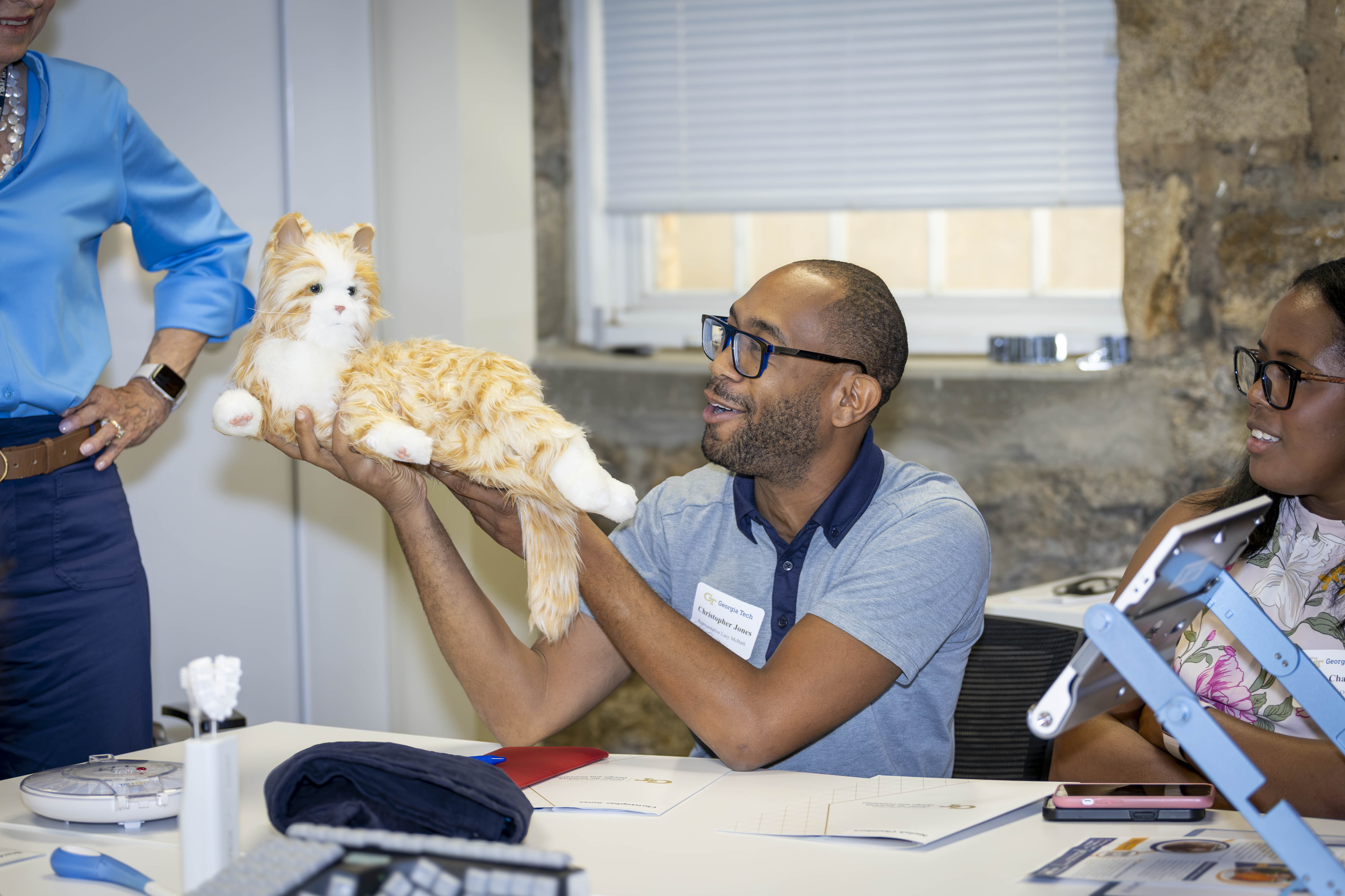 A congressional staffer holding a piece of AT with a smile on his face. The AT is of a lifelike cat. 